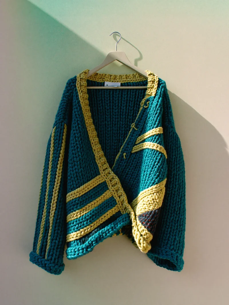 Illustration af en skulpturel strikcardigan på en neutral bøjle